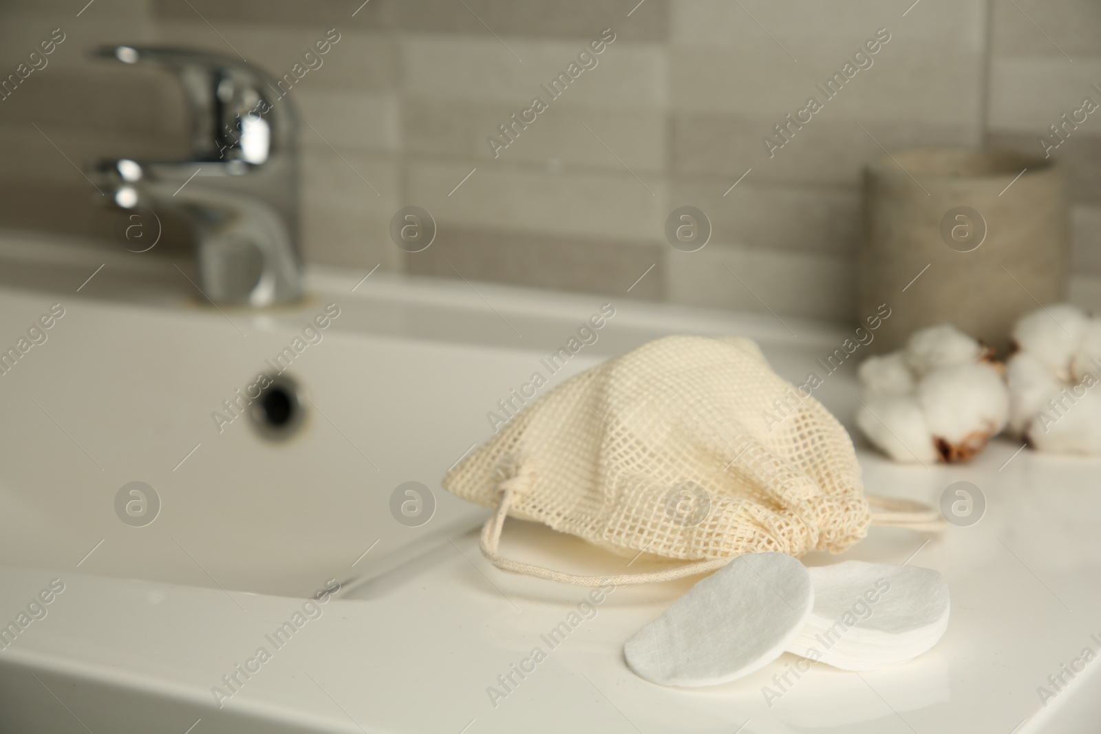 Photo of Cotton pads and bag on sink in bathroom. Space for text