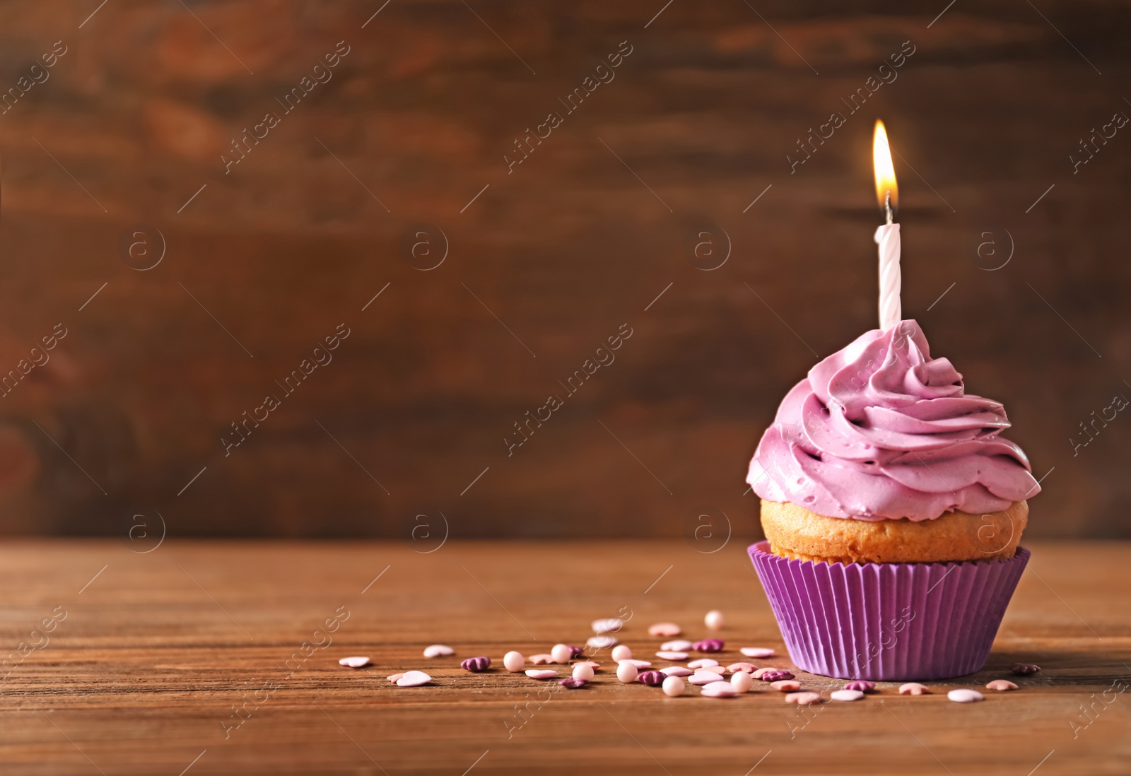 Photo of Delicious birthday cupcake with candle on table