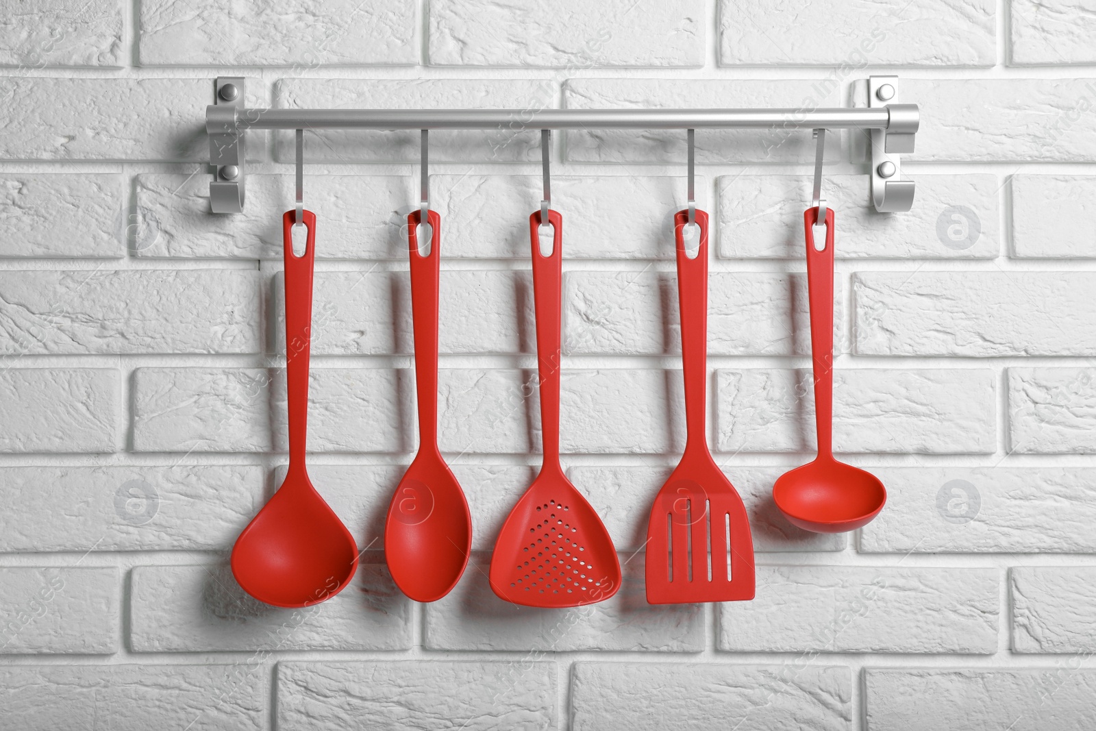 Photo of Rack with kitchen utensils hanging on white brick wall