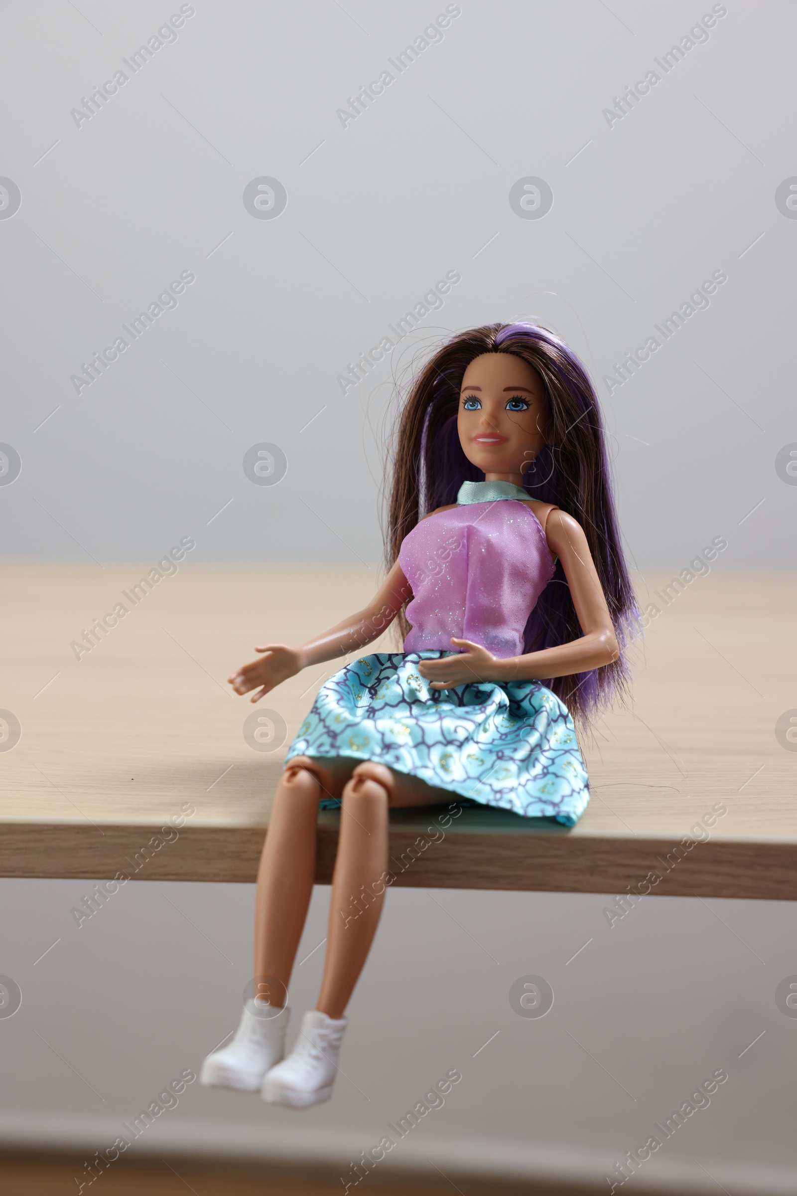Photo of Leiden, Netherlands - September 20, 2023: Beautiful Barbie doll on wooden table against light gray background, space for text