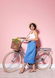 Photo of Portrait of beautiful young woman with bicycle near color wall