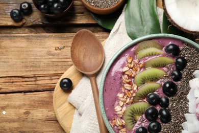Delicious acai smoothie and fruits in bowl served on wooden table, flat lay