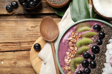 Photo of Delicious acai smoothie and fruits in bowl served on wooden table, flat lay