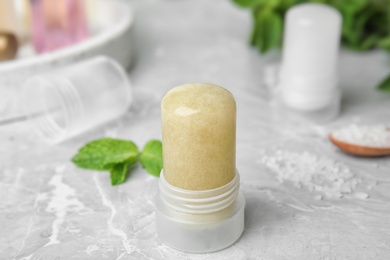 Natural crystal alum deodorant and mint on light grey marble table