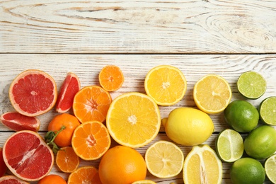 Different citrus fruits on wooden background, top view. Space for text