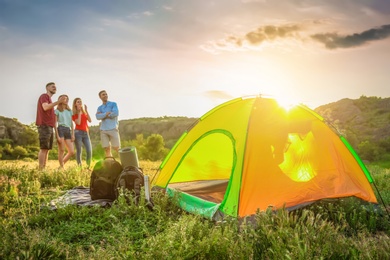 Photo of Camping gear and group of young people in wilderness