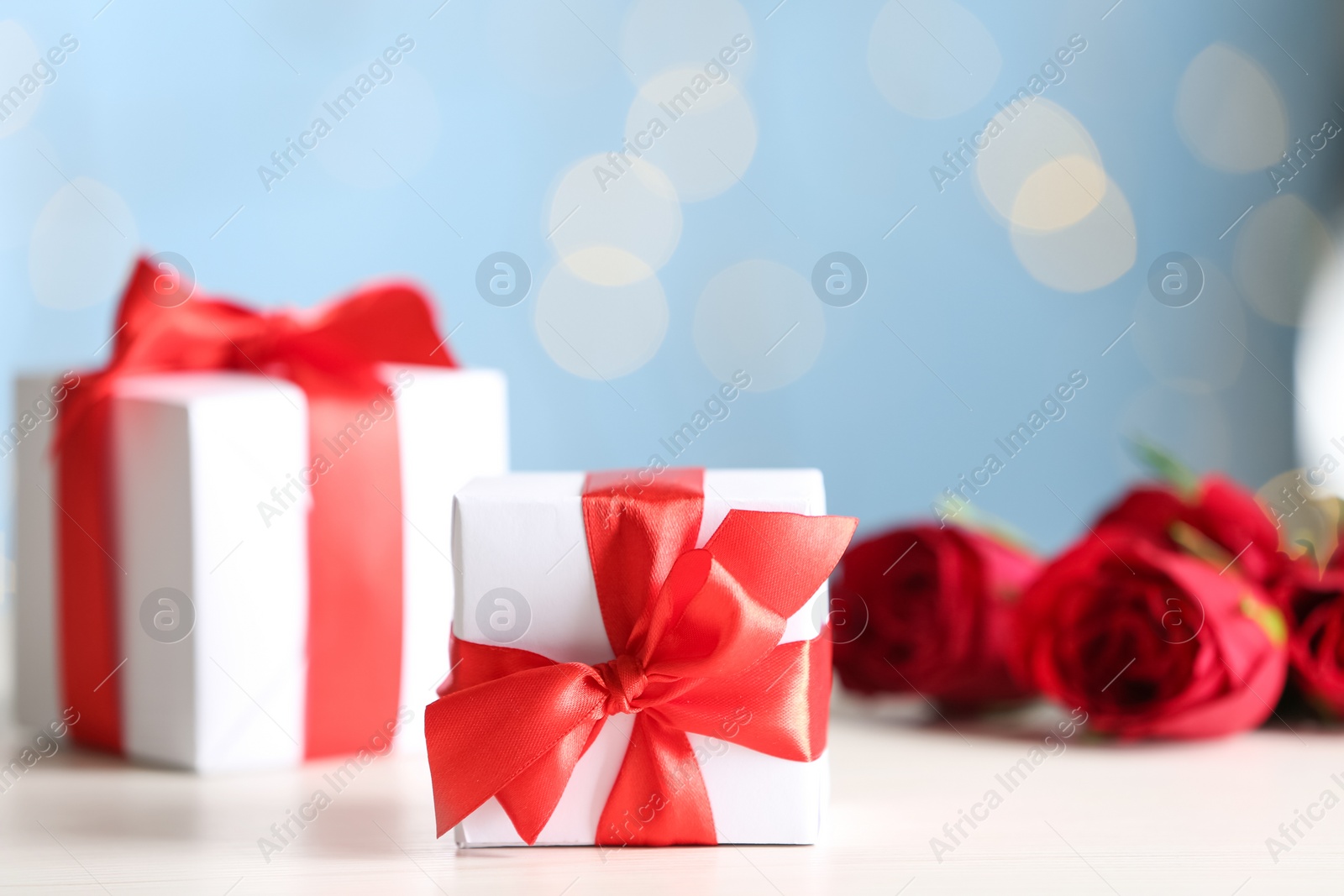 Photo of Gift boxes and roses on light wooden table, space for text. Valentine's Day celebration