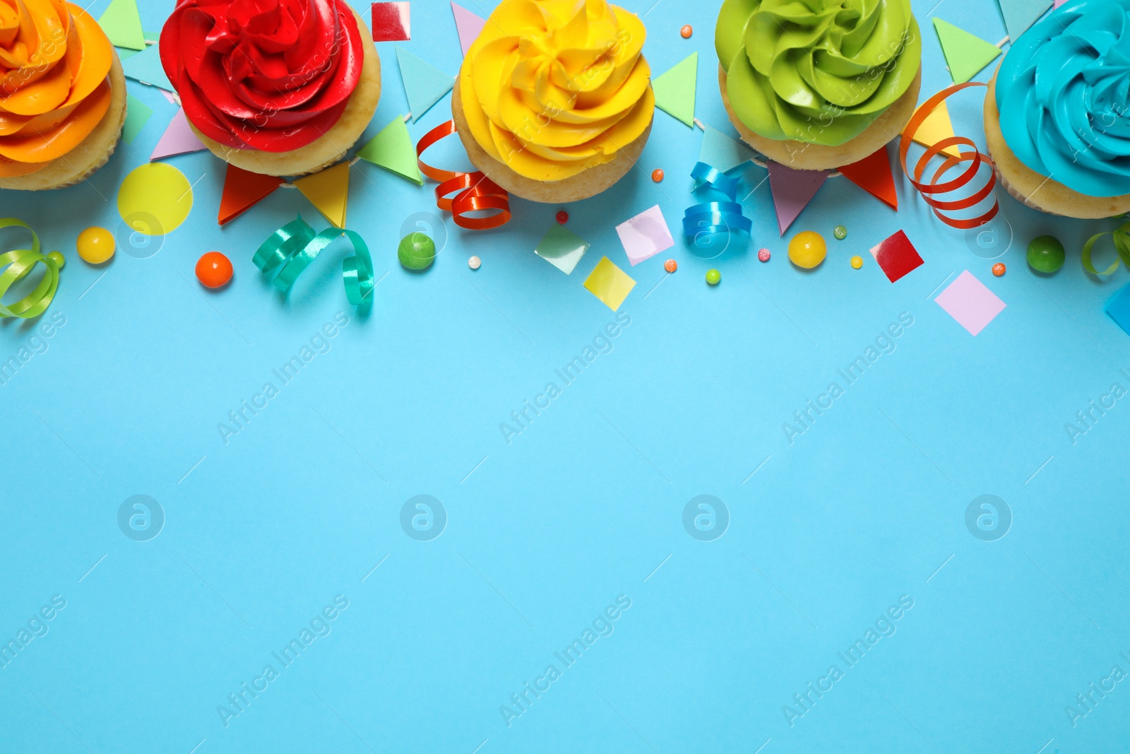 Photo of Colorful birthday cupcakes on light blue background, flat lay. Space for text