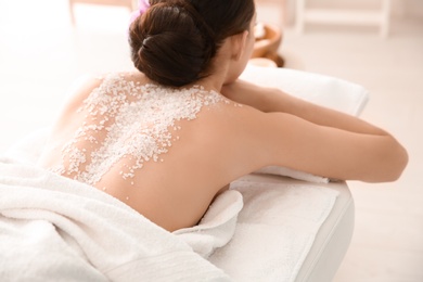 Photo of Beautiful young woman with body scrub on her back in spa salon