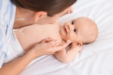 Photo of Woman applying cream onto baby`s face on bed, closeup