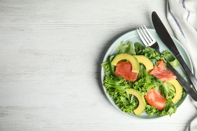 Photo of Delicious avocado salad with salmon on white wooden table, flat lay. Space for text