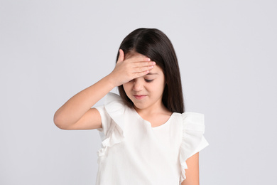 Portrait of cute little girl on light grey background