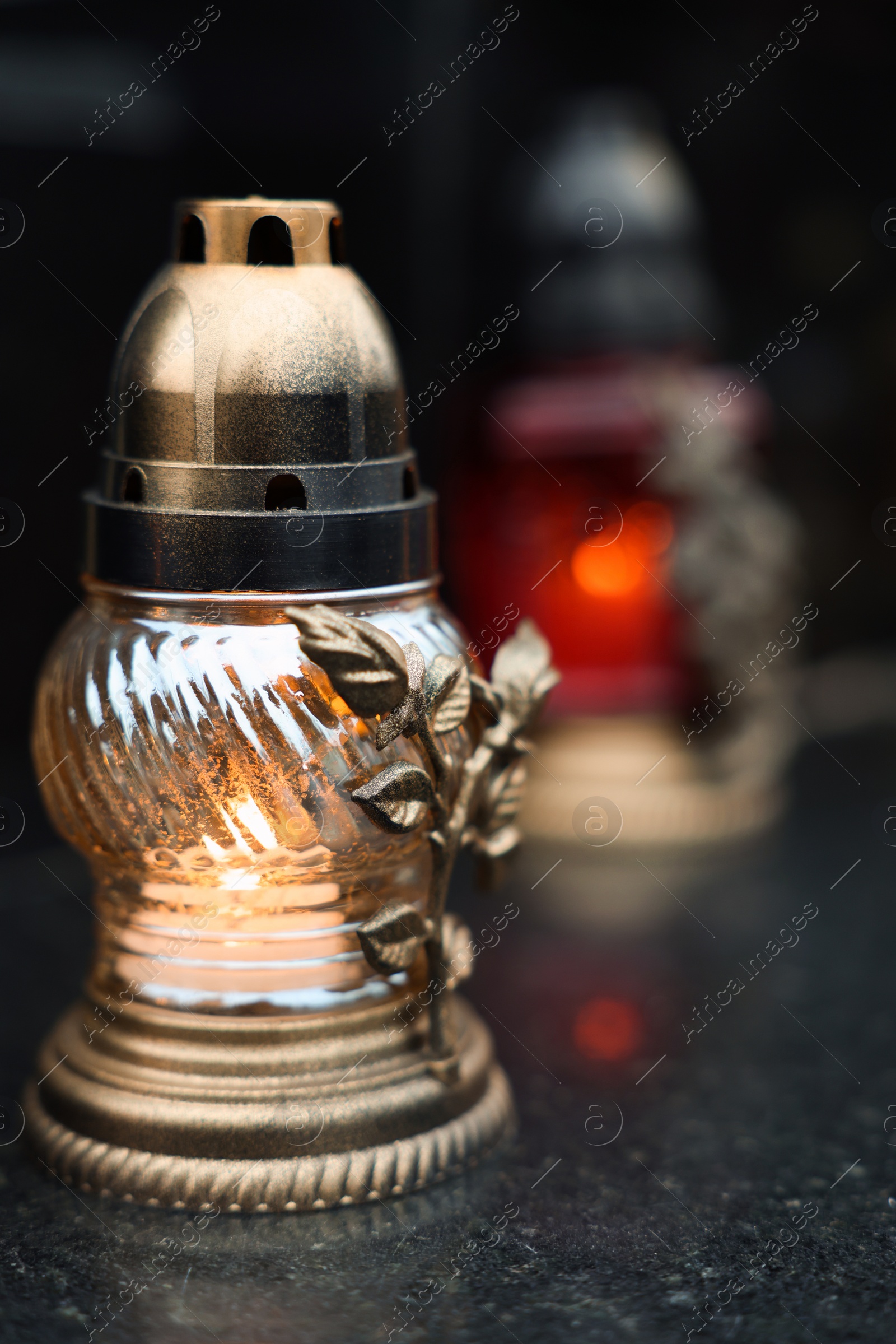 Photo of Grave light on granite surface at cemetery, closeup