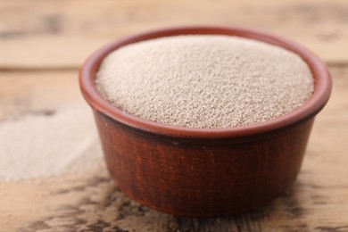 Bowl of active dry yeast on wooden table, closeup