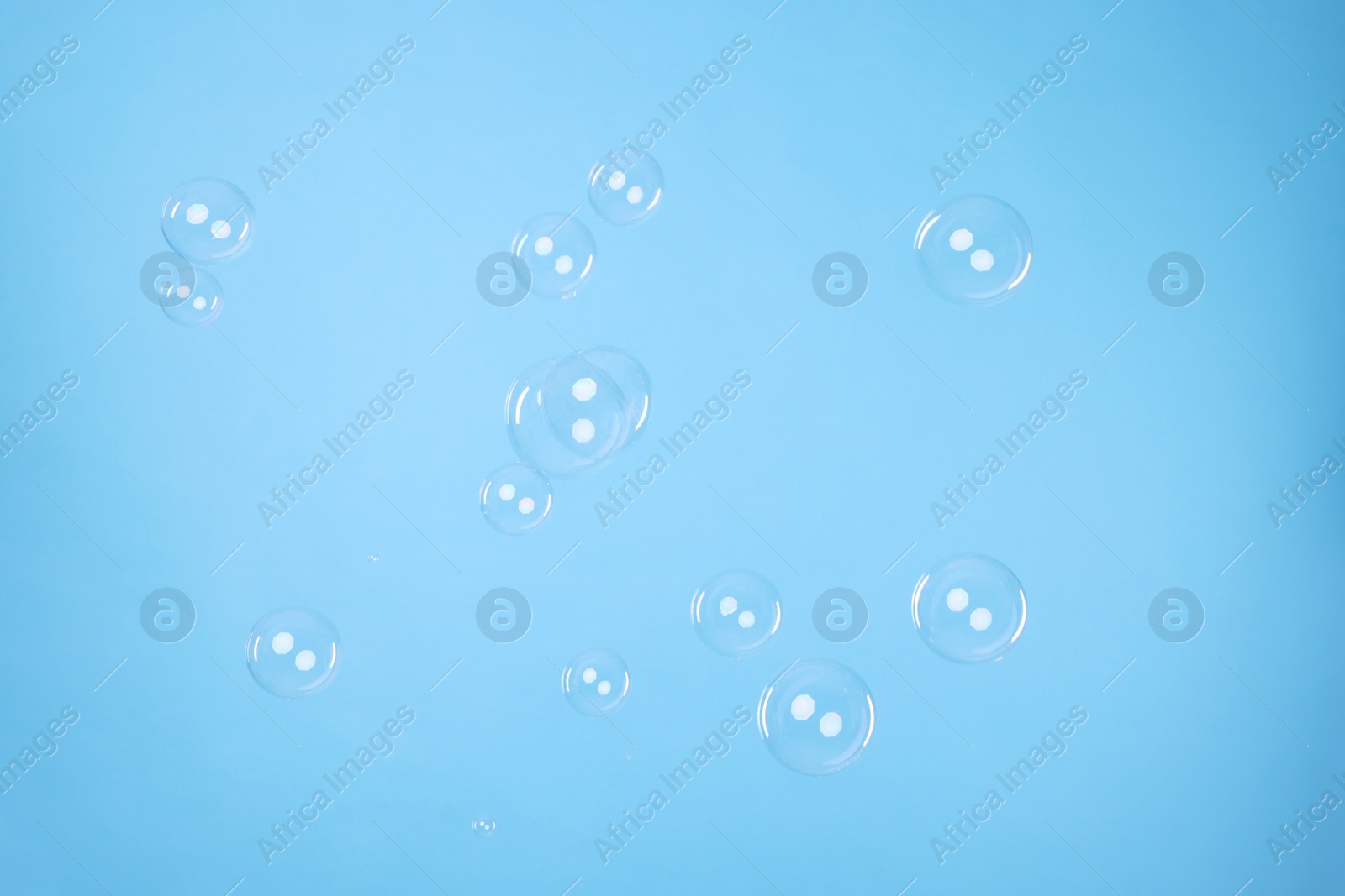 Photo of Many beautiful soap bubbles on light blue background