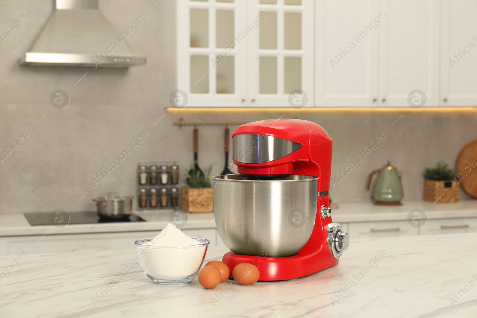 Photo of Modern red stand mixer, eggs and bowl with flour on white marble table in kitchen