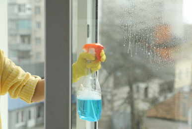 Woman cleaning window at home, closeup view