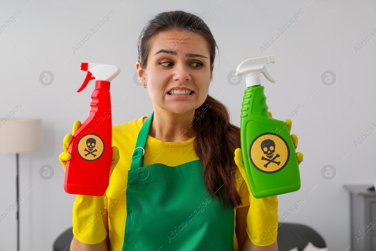 Photo of Woman showing bottles of toxic household chemical with warning signs, closeup
