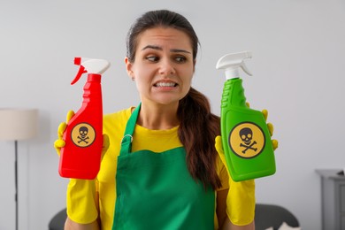 Photo of Woman showing bottles of toxic household chemical with warning signs, closeup