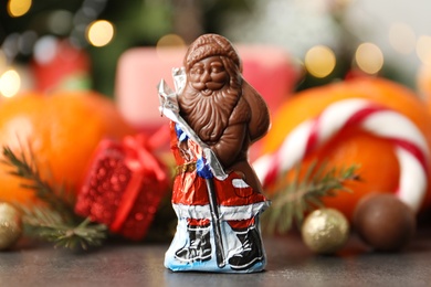 Photo of Chocolate Santa Claus candy against Christmas decorations, sweets and tangerine fruits
