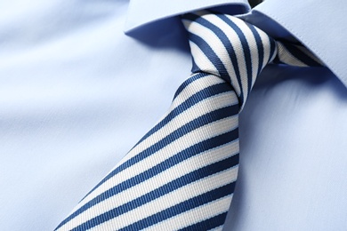 Photo of Striped male necktie on blue shirt, closeup