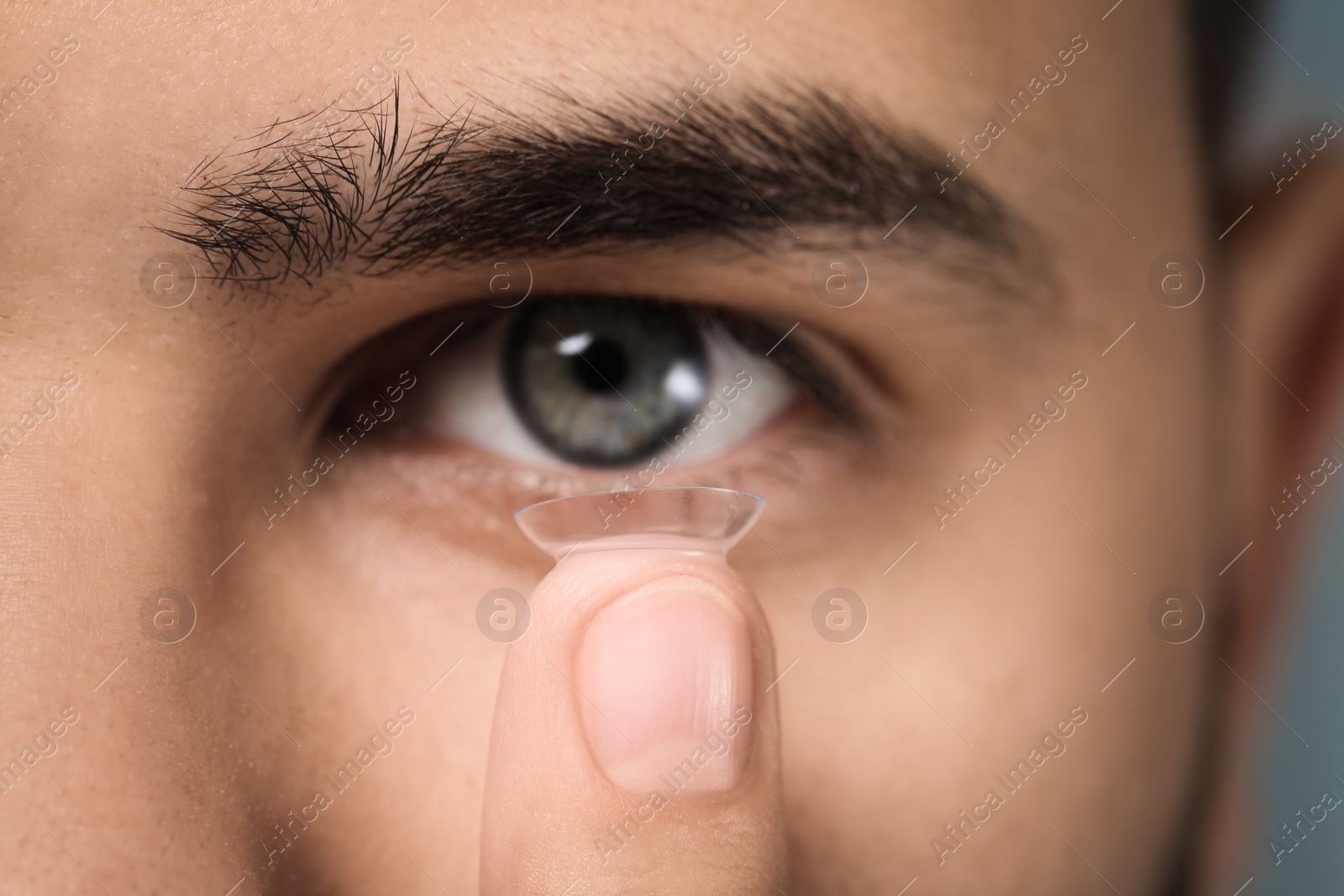 Photo of Closeup view of young man putting in contact lens