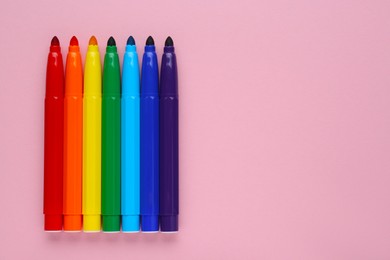 Photo of Many different colorful markers on light pink background, flat lay. Space for text