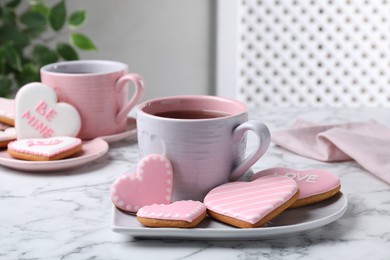 Photo of Delicious heart shaped cookies and cup of tea on white marble table