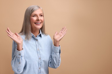 Photo of Portrait of happy middle aged woman on beige background, space for text