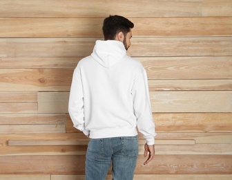 Photo of Young man in sweater at wooden wall. Mock up for design