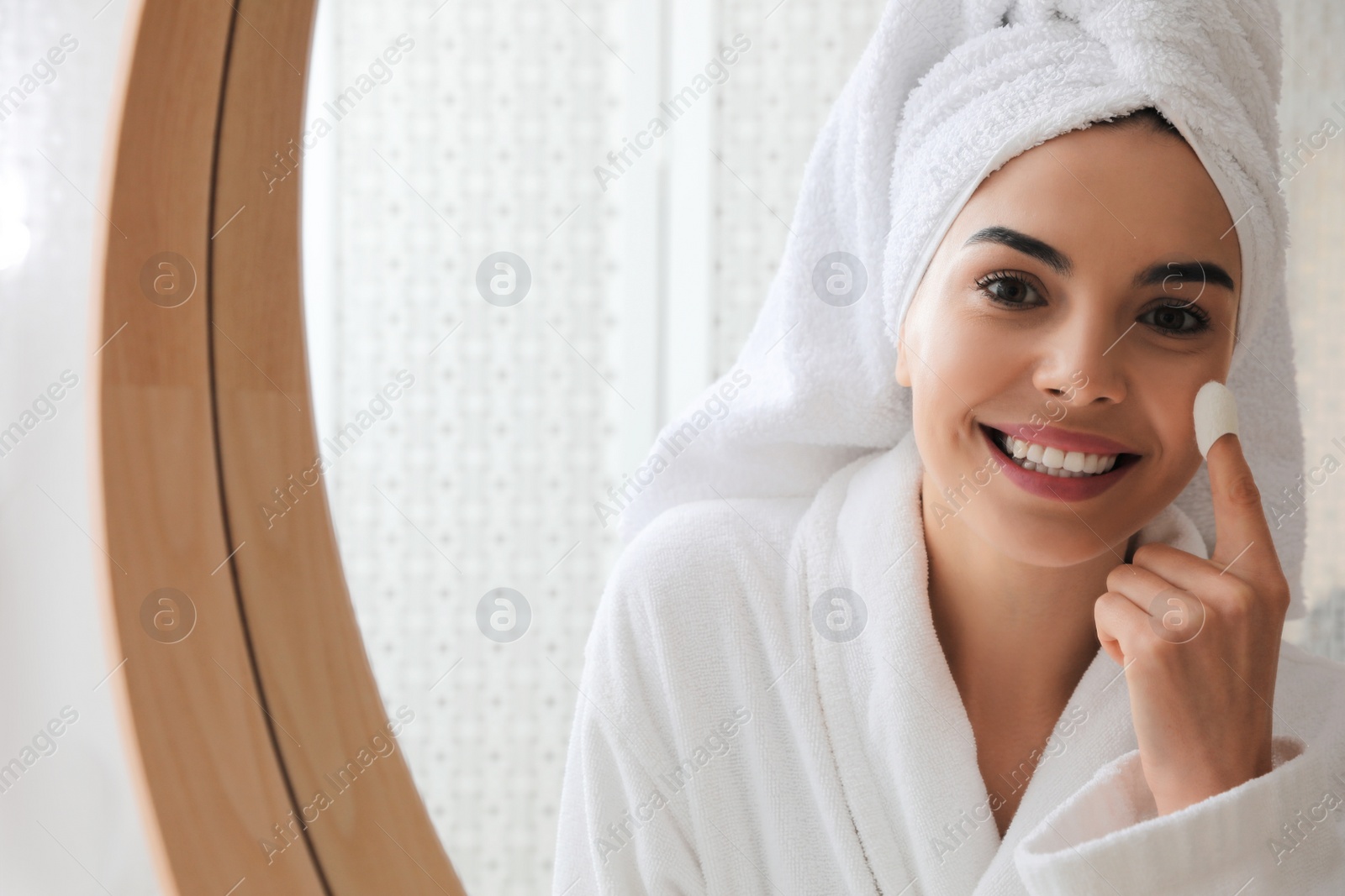 Photo of Woman using silkworm cocoon in skin care routine near mirror at home. Space for text