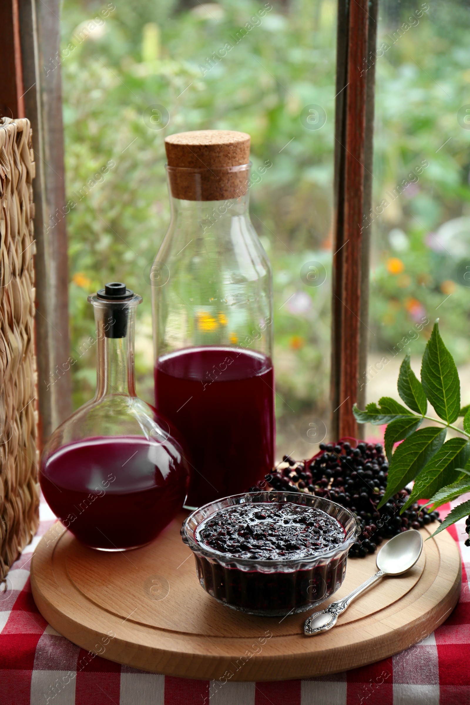 Photo of Elderberry jam and drink with Sambucus berries on table near window