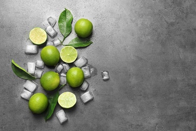 Photo of Composition with fresh ripe limes and ice cubes on gray background, top view