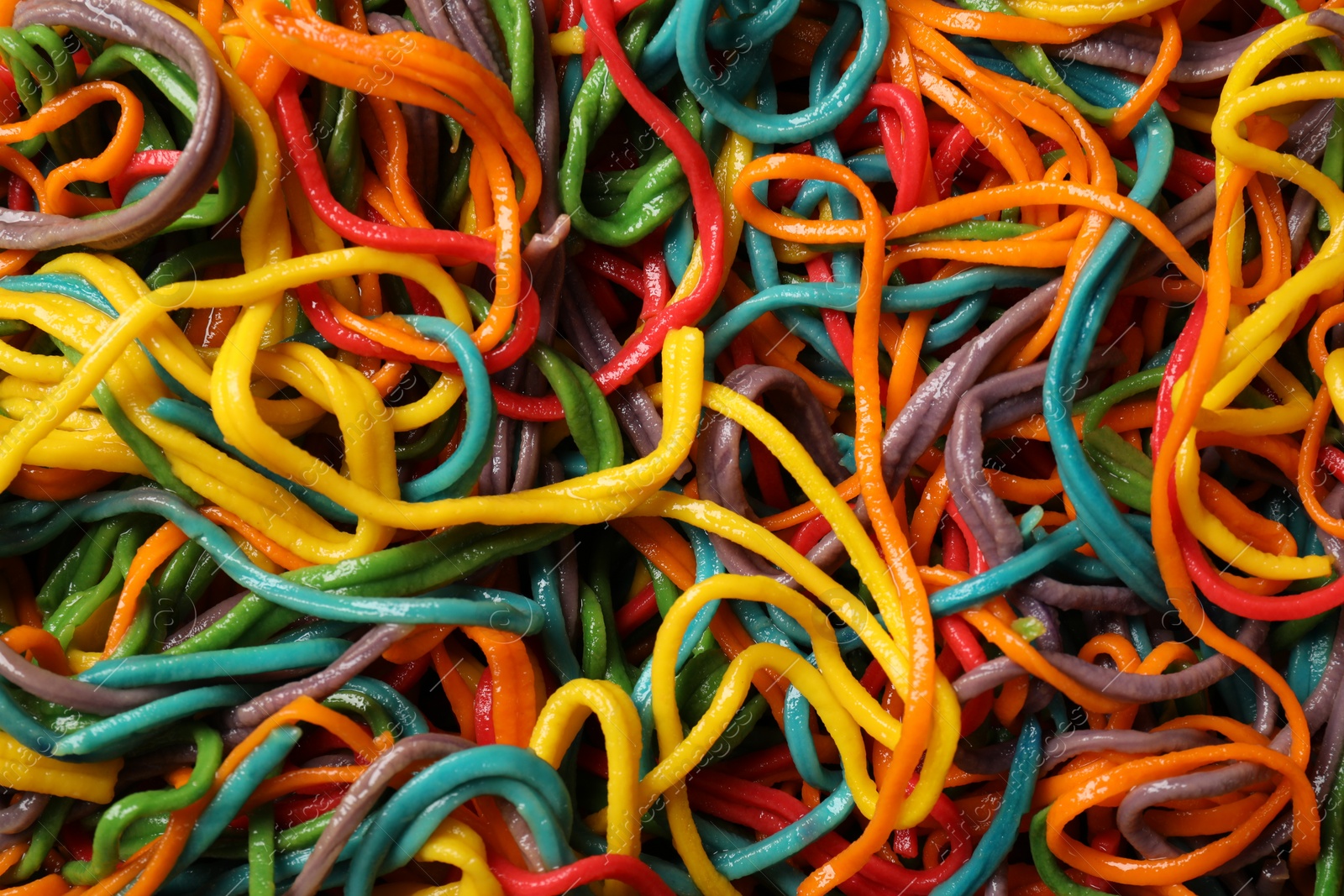 Photo of Spaghetti painted with different food colorings as background, top view