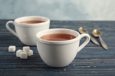 Cups of delicious tea with sugar on table