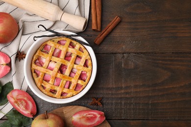 Flat lay composition with tasty apple pie, spices and fruits on wooden table. Space for text