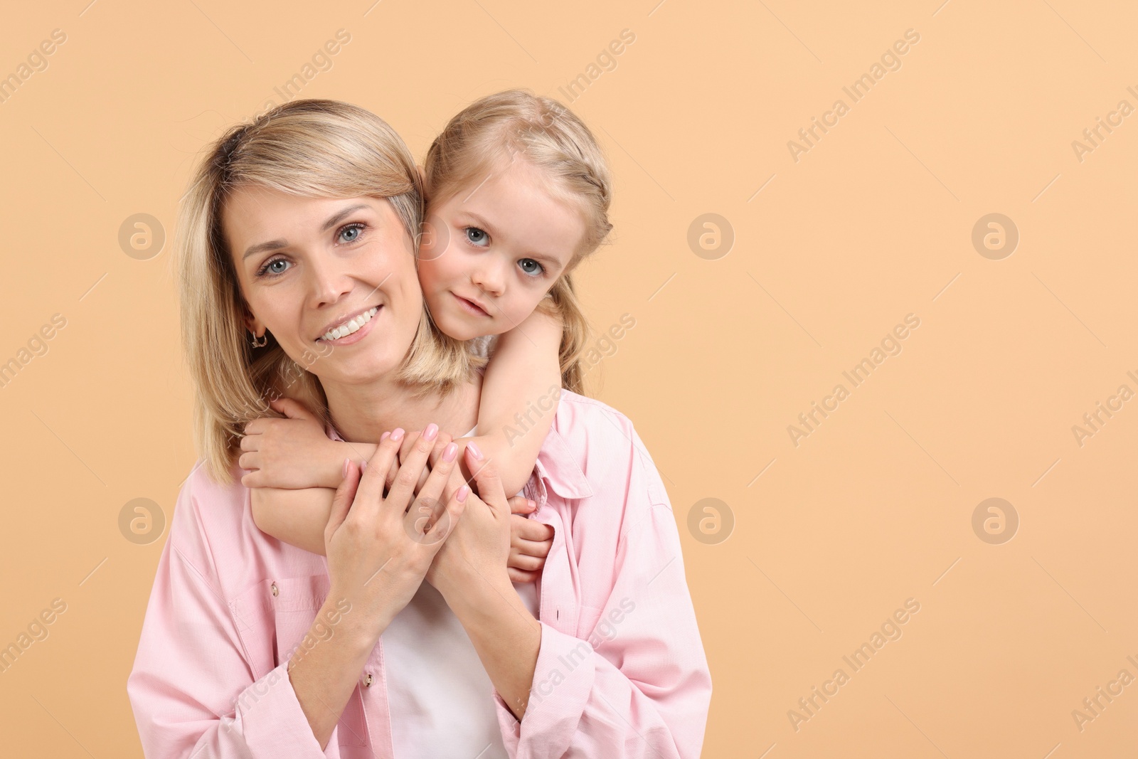 Photo of Family portrait of happy mother and daughter on beige background. Space for text