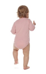 Photo of Cute baby girl in pink bodysuit learning to walk on white background, back view