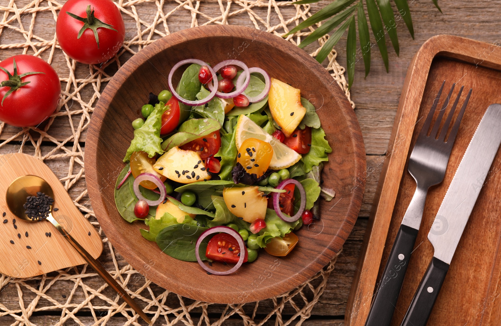 Photo of Delicious salad with peach, green peas and vegetables served on wooden table, flat lay