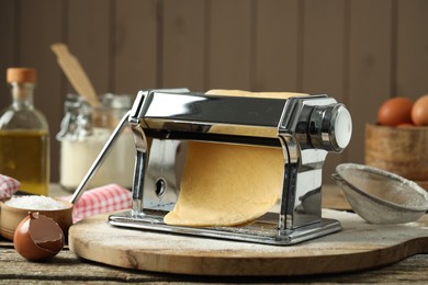 Photo of Pasta maker with raw dough on wooden table