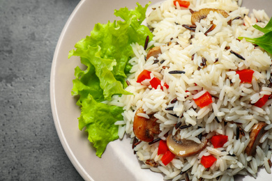 Delicious rice pilaf with mushrooms on grey table, closeup