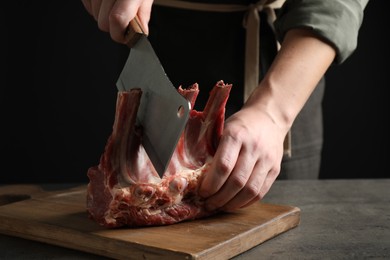 Photo of Man cutting raw ribs at grey table, closeup