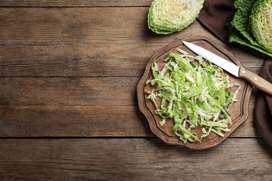 Photo of Cut fresh savoy cabbage on wooden table, flat lay. Space for text