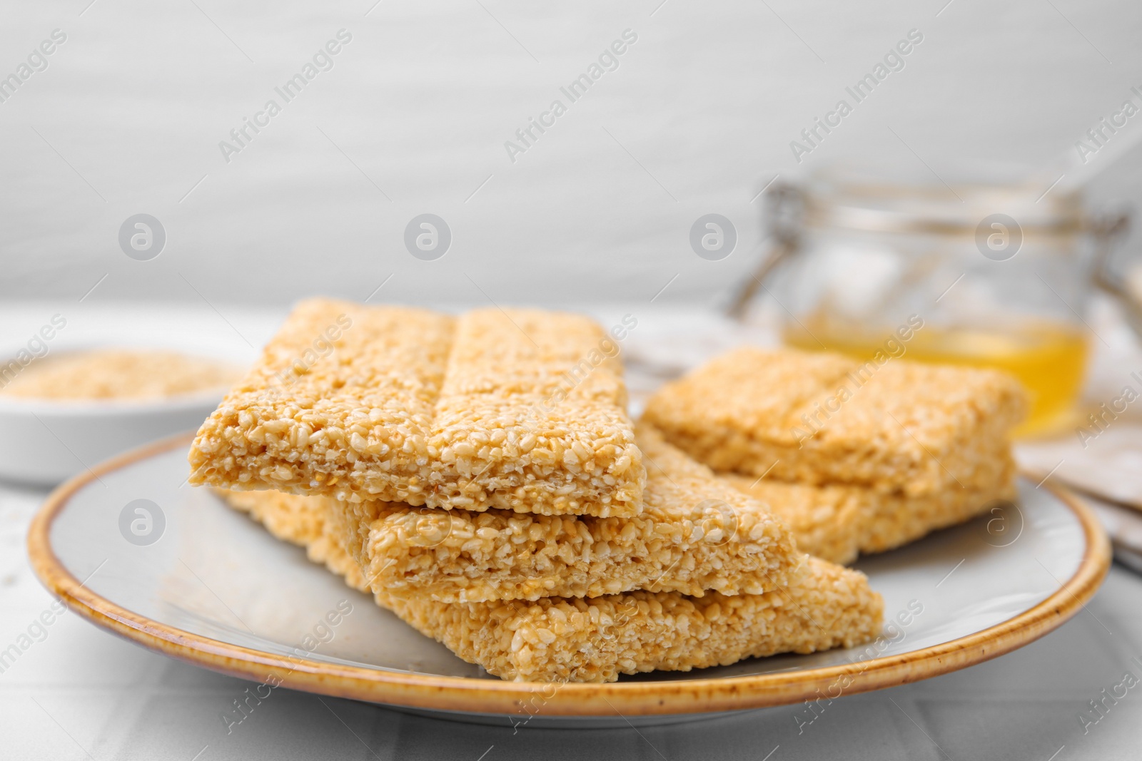 Photo of Plate with delicious sesame kozinaki bars on white table, closeup