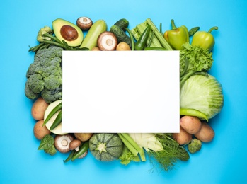 Photo of Blank card and fresh vegetables on light blue background, flat lay. Space for text
