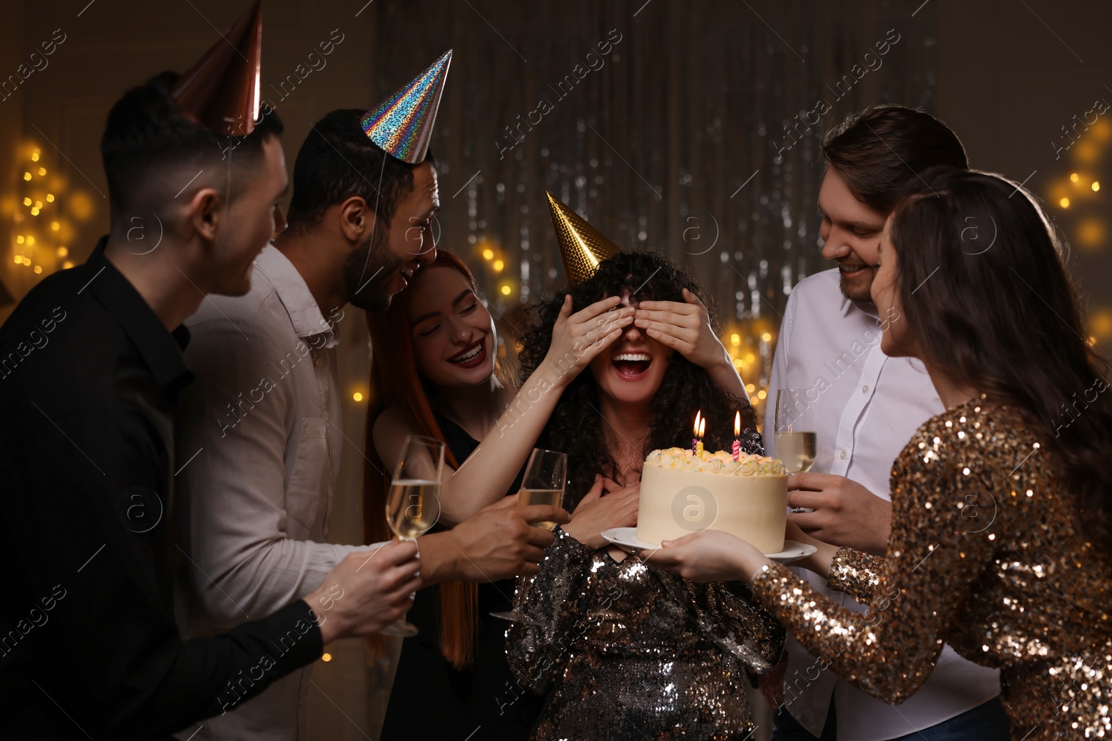 Photo of Happy friends with tasty cake and glasses of sparkling wine celebrating birthday indoors