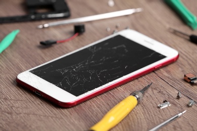 Modern phone with broken display and repair tools on table