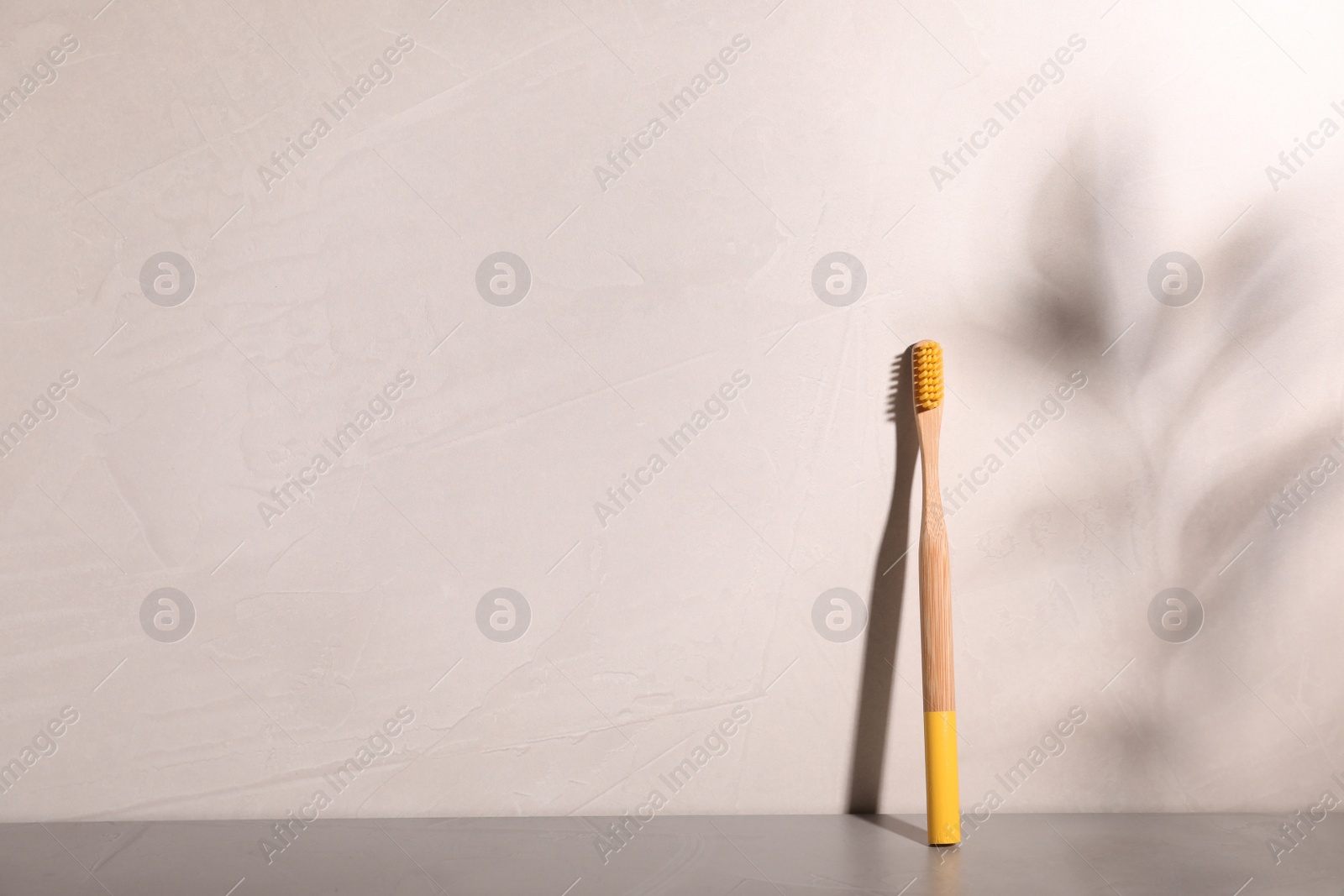 Photo of Bamboo toothbrush on table against grey background. Space for text