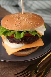 Photo of Tasty cheeseburger with patties and cutlery on wooden table, closeup