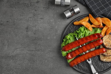 Delicious grilled sausages and vegetables on grey table, flat lay. Space for text